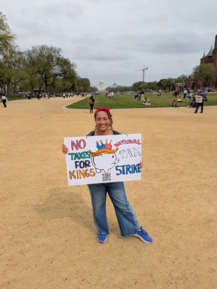 a person holds a sign that reads ‘no taxes for kings national tax strike’