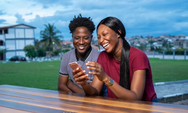 Laughing friends looking at a smartphone.