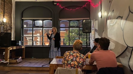 Caroline Butterwick reading on stage at an open mic night