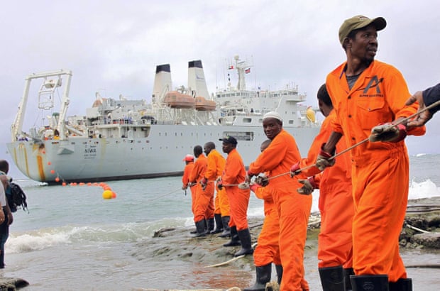 Workers haul part of a fibre optic cable onto shore, Mombasa