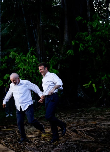 two men in white shirts holding hands in a forest smiling