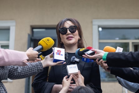 A young Mongolian woman talks as reporters hold microphones towards her
