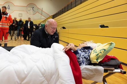 Kai Wegner visits a sports hall housing residents on army camp beds.
