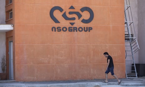 A man walks past the NSO Group logo on a building.