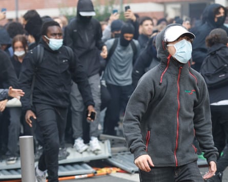 Crowd of young people, mainly male, wearing black and many with masks