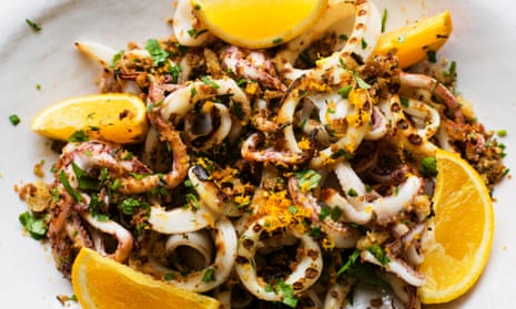 A plate of squid with slices of orange around the plate