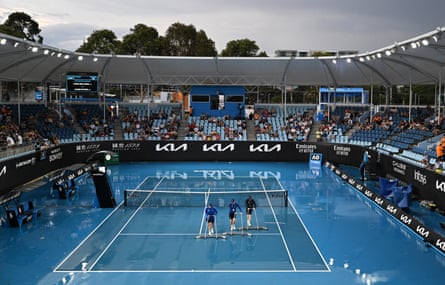 Attendants sweep attempt to sweep the rain from the court on Tuesday after a downpour in Melbourne