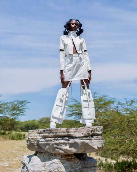 A model stands on a stone wearing a white designer outfit