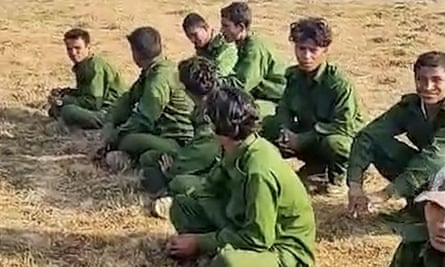 A group of men in green military clothing sitting on the ground.