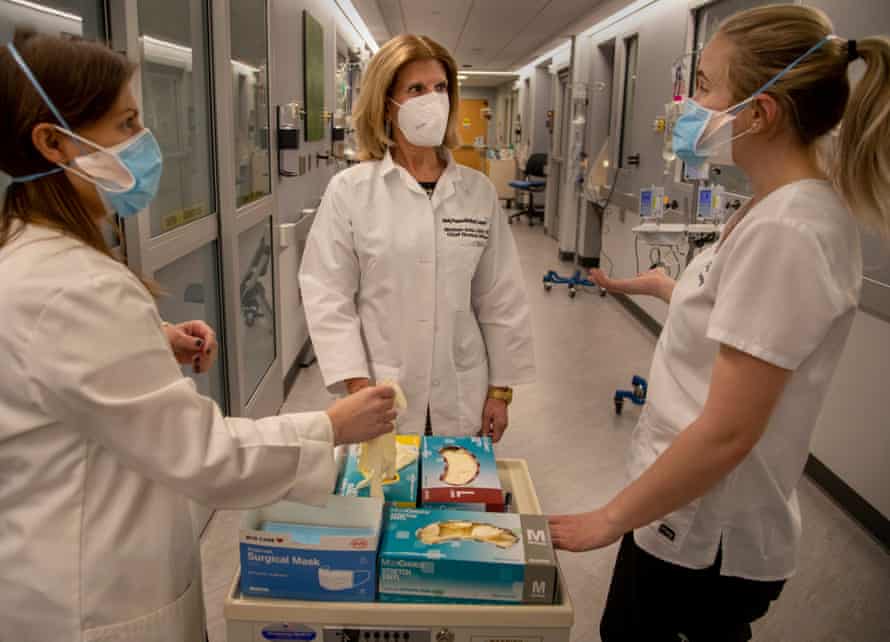 Three women nurses consult in a hospital hallway