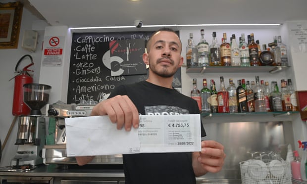 A cafe owner in Florence displays his energy bill amid growing pressures on businesses.
