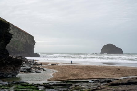 Cornish beach in winter with distant people and dog and a little rocky islet offshore