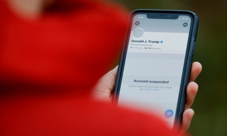 A person holds up a phone showing Trump's suspended Twitter account.