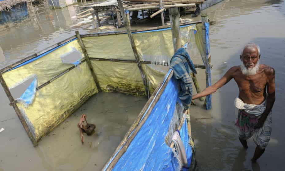 An elderly man stands by a tube well buried in water during high tide in Pratap Nagar, Bangladesh.