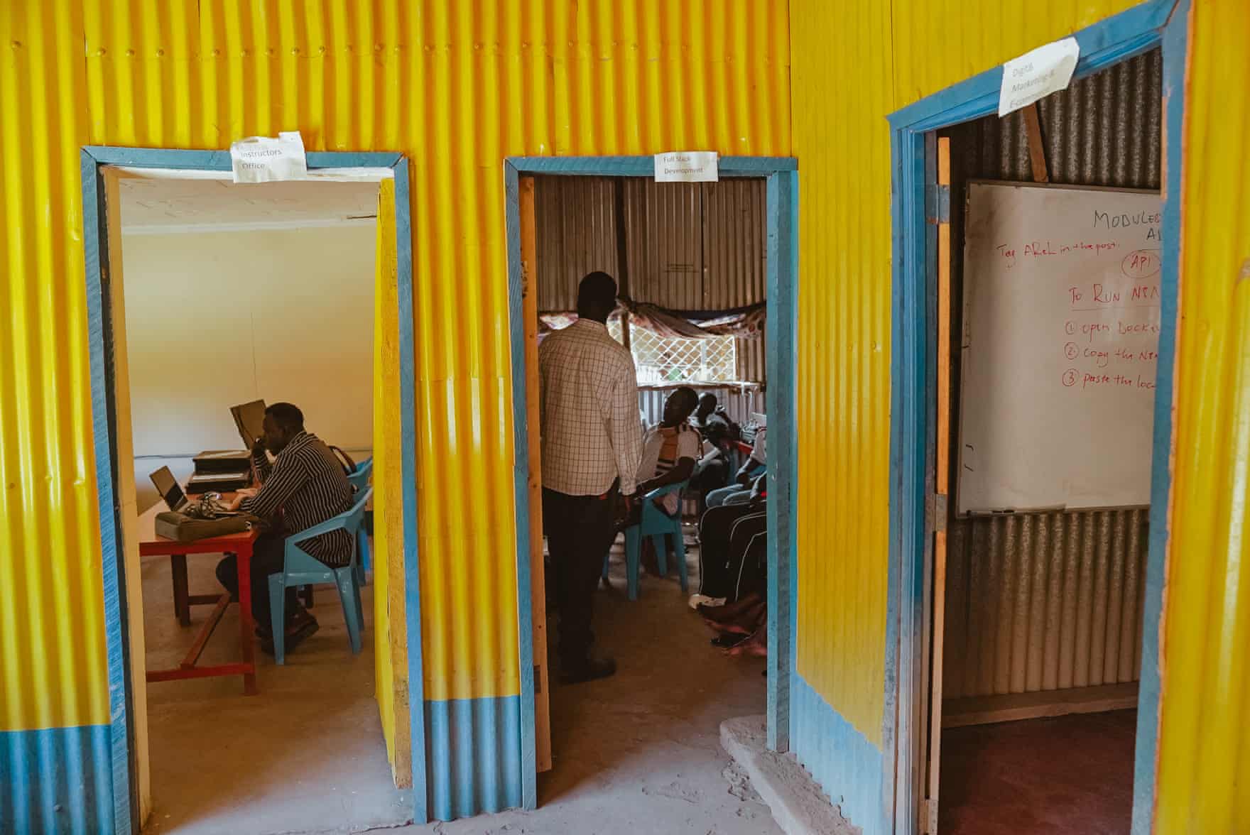 People sit in rooms with colorfully painted walls in yellow and blue.