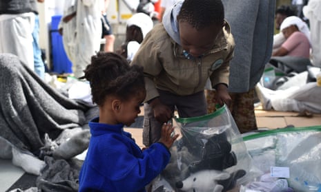 Children pack their cuddly toys in plastic bags as they disembark from a rescue ship in the port of Cagliari, Sardinia.