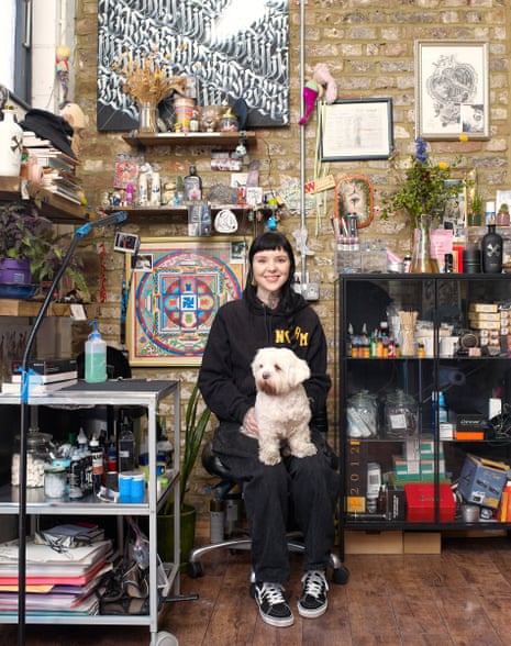 Grace Neutral in her high-ceiling, bare brick Hackney studio with her little white dog on her lap and surrounded by art and art equipment
