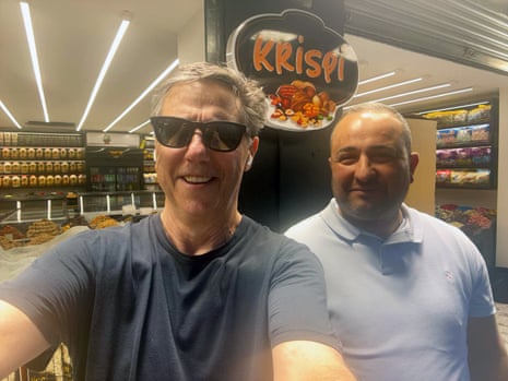 A man with sunglasses takes a selfie with another man.