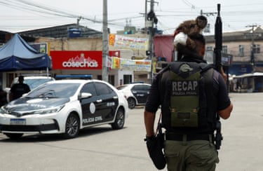 An armed police officer with a small monkey on his head