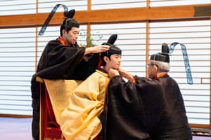 Two men in tradition Japanese robes adjust the headdress of Prince Hisahito