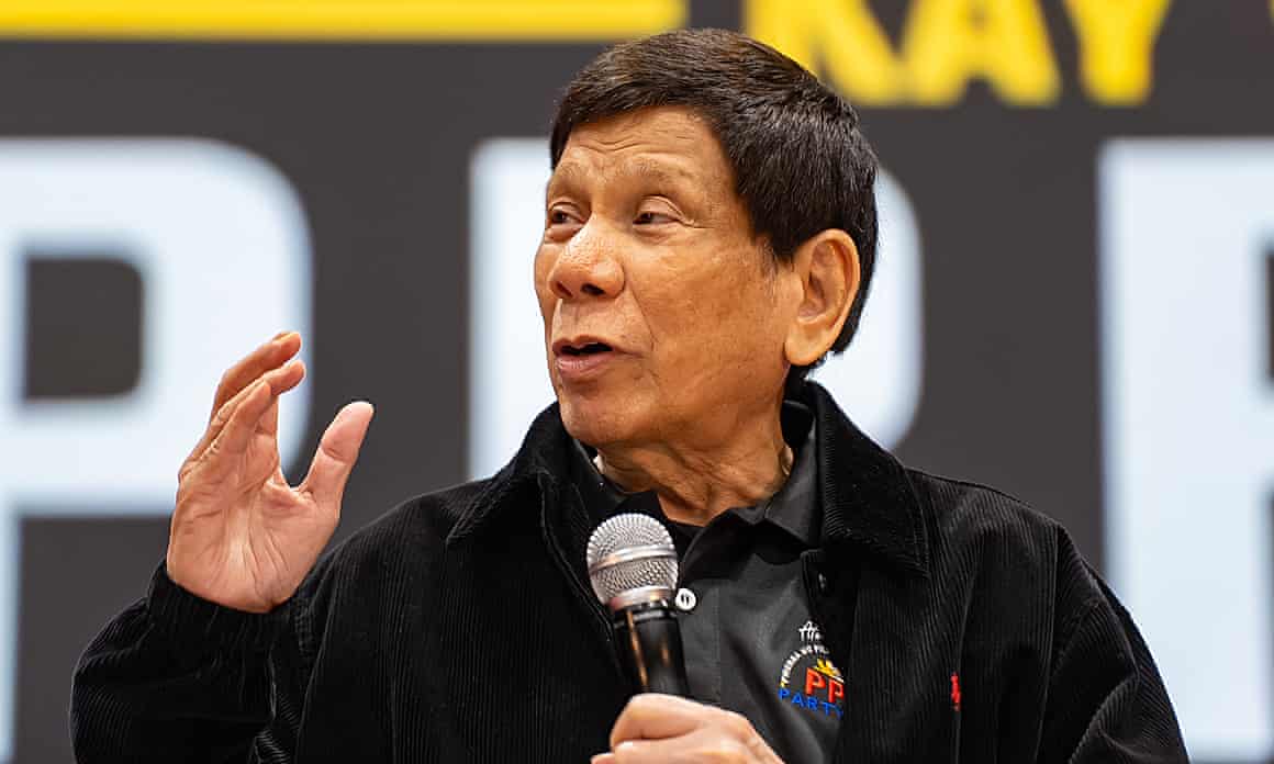 Duterte holding a microphone and gesturing with his other hand