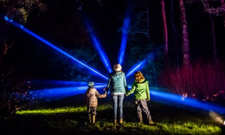 Three figures in front of blue light rays at Westonbirt Arboretum in Wiltshire.
