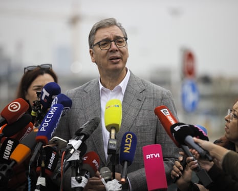 Aleksandar Vučić speaks to journalists, surrounded by numerous microphones at a polling station