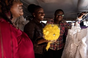 Three smiling women crowd inside the caravan, one holding a yellow bouquet