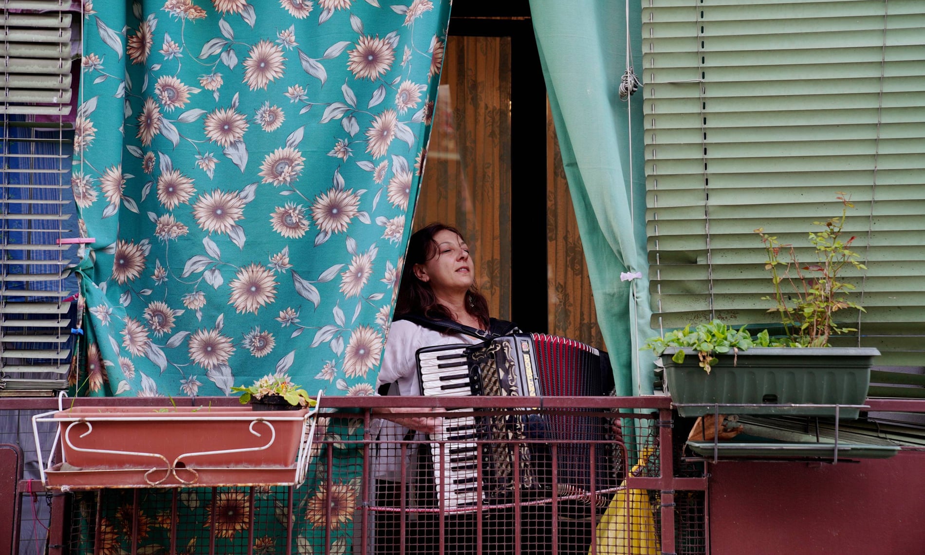 A woman plays the accordion on the balcony of her home in Milan, as part of a movement throughout Italy attempting to bring people together and lift spirits during the coronavirus lockdown.