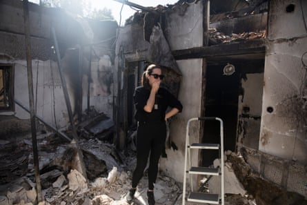 A woman stands in rubble looking shocked and sad