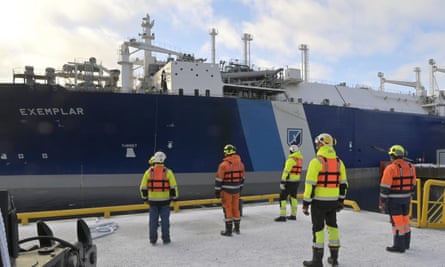 People stand looking at a floating liquefied natural gas LNG terminal 