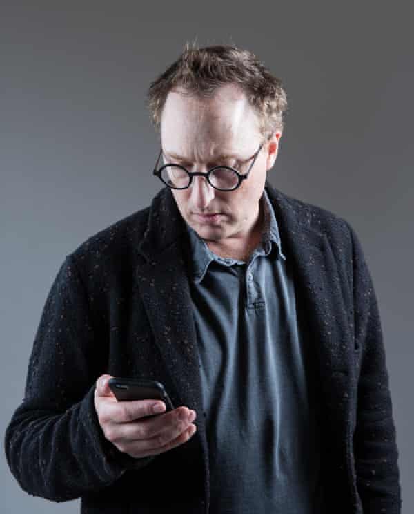 Jon Ronson looking at his mobile phone