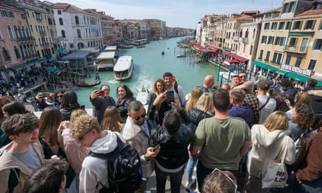 Tourists take pictures on the Rialto bridge with the canal in the background