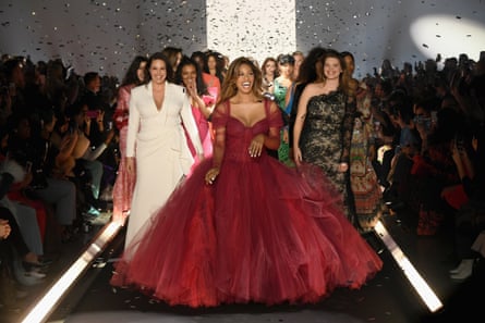 Cox laughing and wearing a red tulle dress with full skirt and surrounded by other models