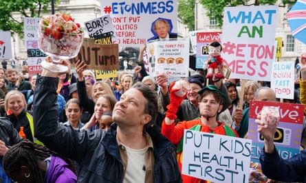 Chef Jamie Oliver holds up an Eton mess pudding prop among a crowd of campaigners outside Downing Street who are hold signs that read: ‘put kids health first’