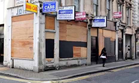 A woman walks past boarded up shops in central London.