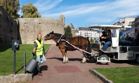 Julien picks up a rubbish from a public bin during a horse-drawn collection in Hennebont.