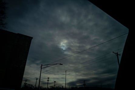 View of the sun partially obscured behind clouds.