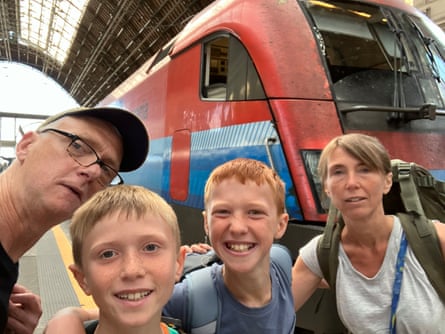Two adults and two children in front of a train on a platform