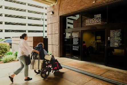 A woman wheels her son into a treatment center