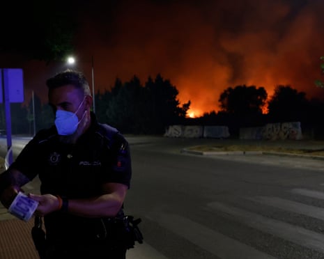 A policeman cordons off an area during a wildfire as the Community of Madrid has declared operational status 2 for the Special Emergency Civil Protection Plan for Forest Fires (Infoma) due to the vegetation fire in the Madrid town of Tres Cantos, Spain.