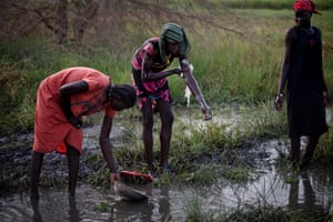 At the nearby swamp, two women wash and another collects water in a plastic container