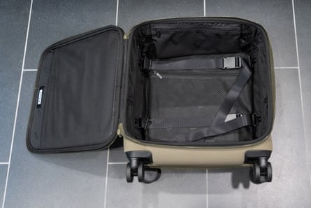 Open tan suitcase on tile floor