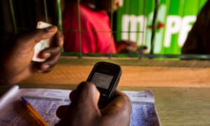 An employee uses a  mobile phone inside an M-Pesa store in Nairobi