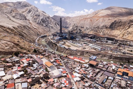 An aerial image of a small town in the foreground and a smelting plant in the background, located in a valley in the Andes