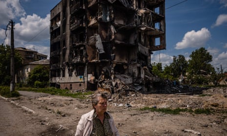 A woman walks past a destroyed apartment building in the town of Borodyanka.