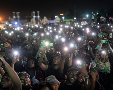 Fans cheer while filming with their phones as Afrobeats star, Davido, performs on stage in Accra at the AfroFuture festival in December 2023.