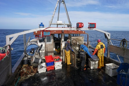 Three men in oilskins on the deck of a large fishing boat at sea