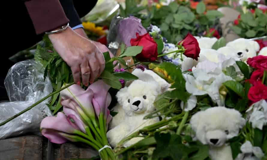 A woman lays flowers in front of the Fields Mall.