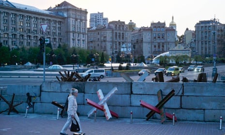 A woman dressed all in white walks by anti-tank hedgehogs and concrete blocks on display in Independence Square in Kyiv. 